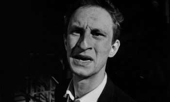 Movie still from “Man Bites Dog” (1992), directed by Benoît Poelvoorde – Black and white photograph of a man in a suit; Close Up shot, Low angle