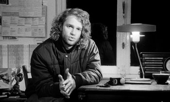 Movie still from “Man Bites Dog” (1992), directed by Benoît Poelvoorde – Black and white photograph of a man sitting at a table; Close Up shot, Over the shoulder angle