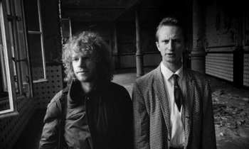 Movie still from “Man Bites Dog” (1992), directed by Benoît Poelvoorde – A black and white photo of two men standing next to each other; Close Up shot, Low angle