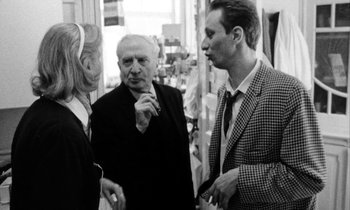 Movie still from “Man Bites Dog” (1992), directed by Benoît Poelvoorde – A group of people standing next to each other talking; Medium shot, Over the shoulder angle