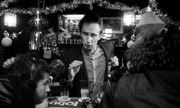 Movie still from “Man Bites Dog” (1992), directed by Benoît Poelvoorde – A group of people sitting around a table; Medium shot, Over the shoulder angle
