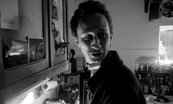Movie still from “Man Bites Dog” (1992), directed by Benoît Poelvoorde – A black - and - white photo of a man in front of a mirror; Close Up shot, Low angle