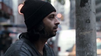 Movie still from “Man Push Cart” (2005), directed by Ramin Bahrani – A person wearing a hat near a pole; Close Up shot, Over the shoulder angle