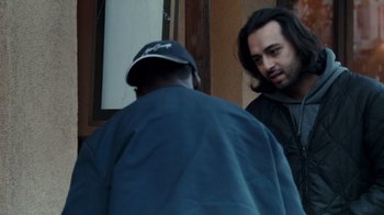 Movie still from “Man Push Cart” (2005), directed by Ramin Bahrani – Two men standing next to each other near a building; Medium shot, Over the shoulder angle