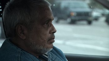Movie still from “Man Push Cart” (2005), directed by Ramin Bahrani – An older man sitting in the back seat of a car; Close Up shot, Over the shoulder angle