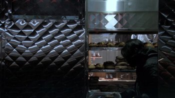 Movie still from “Man Push Cart” (2005), directed by Ramin Bahrani – A person standing in front of some food in a kitchen; Medium shot, High angle