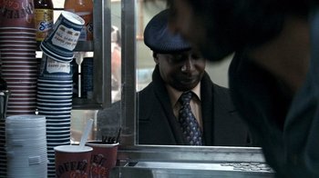 Movie still from “Man Push Cart” (2005), directed by Ramin Bahrani – A man wearing a hat and a tie is sitting in front of a window; Medium shot, Over the shoulder angle
