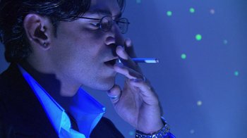 Movie still from “Man Push Cart” (2005), directed by Ramin Bahrani – A man smoking a cigarette while holding a cell phone to his ear; Extreme Close Up shot, Low angle