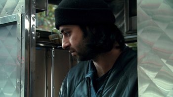 Movie still from “Man Push Cart” (2005), directed by Ramin Bahrani – A person wearing a hat; Close Up shot, Over the shoulder angle