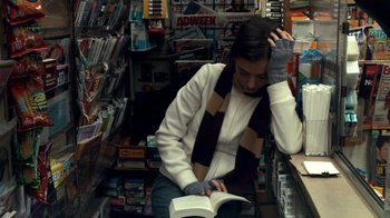 Movie still from “Man Push Cart” (2005), directed by Ramin Bahrani – A woman sitting on a chair reading a book; Medium shot, High angle