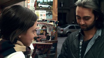 Movie still from “Man Push Cart” (2005), directed by Ramin Bahrani – A man and a woman talking in front of magazines; Close Up shot, Over the shoulder angle
