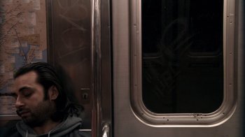 Movie still from “Man Push Cart” (2005), directed by Ramin Bahrani – A man sitting on a train looking out the window; Medium shot, Over the shoulder angle