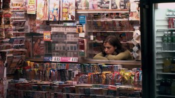 Movie still from “Man Push Cart” (2005), directed by Ramin Bahrani – A woman sitting in a store looking at a lot of magazines; Medium shot, Over the shoulder angle