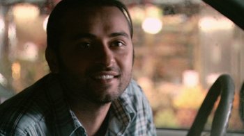Movie still from “Man Push Cart” (2005), directed by Ramin Bahrani – A person smiling for the camera; Close Up shot, Over the shoulder angle