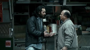 Movie still from “Man Push Cart” (2005), directed by Ramin Bahrani – Two men are talking in a restaurant kitchen; Medium shot, Over the shoulder angle