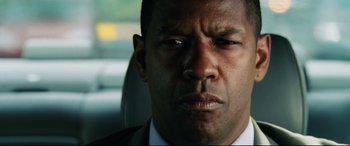 Movie still from “Man on Fire” (2004), directed by Tony Scott – A man in a suit sitting in a car looking sad; Close Up shot, Over the shoulder angle