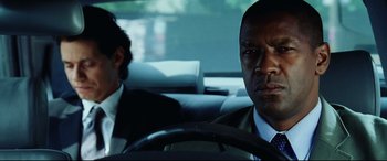 Movie still from “Man on Fire” (2004), directed by Tony Scott – A man in a suit sitting in the driver's seat of a car; Close Up shot, Over the shoulder angle