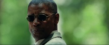 Movie still from “Man on Fire” (2004), directed by Tony Scott – A person wearing a suit and sunglasses; Close Up shot, Low angle