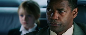 Movie still from “Man on Fire” (2004), directed by Tony Scott – A man and a woman sitting in a car looking at the camera; Close Up shot, Over the shoulder angle