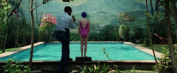 Movie still from “Man on Fire” (2004), directed by Tony Scott – A man taking a picture of a woman standing in front of a swimming pool; Wide shot, Over the shoulder angle