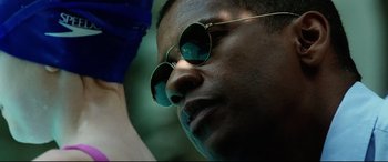 Movie still from “Man on Fire” (2004), directed by Tony Scott – A person wearing round sunglasses; Close Up shot, Over the shoulder angle