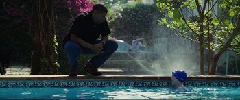 Movie still from “Man on Fire” (2004), directed by Tony Scott – A man kneeling down next to a swimming pool; Wide shot, Low angle