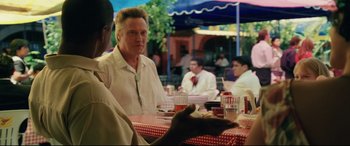 Movie still from “Man on Fire” (2004), directed by Tony Scott – A group of people sitting at a table with plates of food; Medium shot, Over the shoulder angle