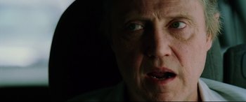 Movie still from “Man on Fire” (2004), directed by Tony Scott – An older man with a very dark background; Close Up shot, Over the shoulder angle