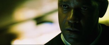 Movie still from “Man on Fire” (2004), directed by Tony Scott – A man's face in a dark room; Close Up shot, Low angle