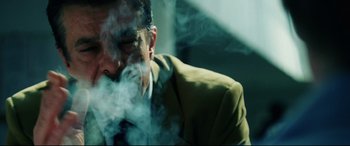 Movie still from “Man on Fire” (2004), directed by Tony Scott – A man smoking a cigarette while sitting down; Close Up shot, Low angle