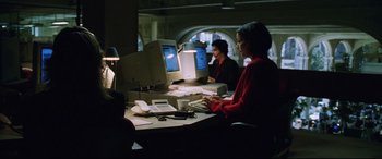 Movie still from “Man on Fire” (2004), directed by Tony Scott – A woman sitting at a table with a computer; Medium shot, High angle