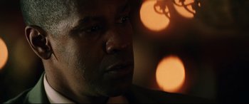 Movie still from “Man on Fire” (2004), directed by Tony Scott – A man's face in front of lights; Close Up shot, Over the shoulder angle