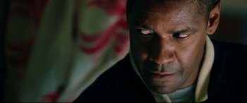 Movie still from “Man on Fire” (2004), directed by Tony Scott – A man's face in a dark room; Close Up shot, Over the shoulder angle