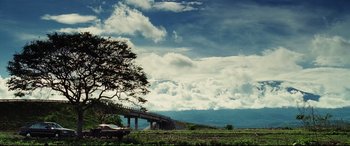 Movie still from “Man on Fire” (2004), directed by Tony Scott – A car is parked on the side of a road; Extreme Wide shot, Low angle