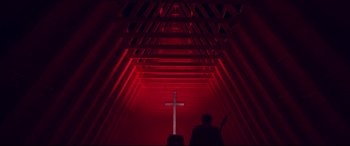 A man standing in a dark room with a cross