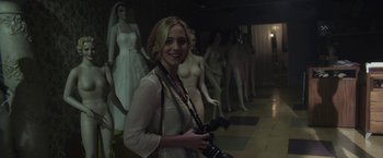 A woman holding a camera in front of a group of mannequins