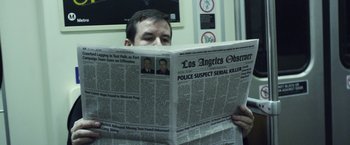 Movie still from “Maniac” (2012), directed by Franck Khalfoun – A man reading a newspaper on a train; Medium shot, Over the shoulder angle