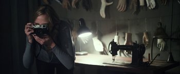 Movie still from “Maniac” (2012), directed by Franck Khalfoun – A woman standing in front of a sewing machine in a room; Medium shot, Over the shoulder angle