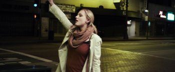 Movie still from “Maniac” (2012), directed by Franck Khalfoun – A woman in a white jacket and a brown scarf is on the street; Medium shot, Low angle