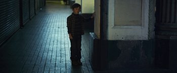 Movie still from “Maniac” (2012), directed by Franck Khalfoun – A young boy standing on a brick walkway; Wide shot, High angle