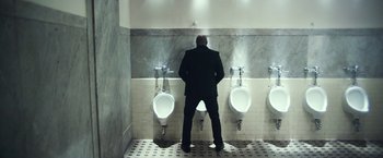 Movie still from “Maniac” (2012), directed by Franck Khalfoun – A man standing in front of urinals in a bathroom; Wide shot, Low angle