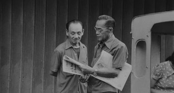 Two men are looking at a newspaper together