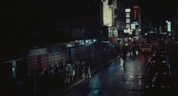 A group of people walking down a street at night