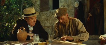 Movie still from “Manon of the Spring” (1986), directed by Claude Berri – Two men are sitting at a table and looking at a cell phone; Medium shot, Over the shoulder angle