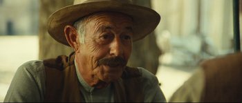 Movie still from “Manon of the Spring” (1986), directed by Claude Berri – An old man wearing a hat and a vest; Close Up shot, Over the shoulder angle