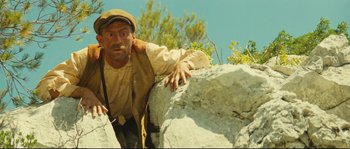 Movie still from “Manon of the Spring” (1986), directed by Claude Berri – A man leaning on a large rock on top of a hill; Medium shot, Low angle