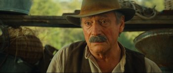 Movie still from “Manon of the Spring” (1986), directed by Claude Berri – An old man with a mustache wearing a cowboy hat; Close Up shot, Over the shoulder angle