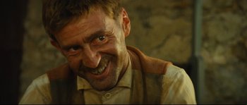 Movie still from “Manon of the Spring” (1986), directed by Claude Berri – A person with a beard smiling; Close Up shot, Low angle