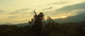 Movie still from “Manon of the Spring” (1986), directed by Claude Berri – A man holding a rifle in a field at dusk; Extreme Wide shot, Low angle
