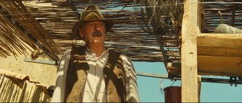 Movie still from “Manon of the Spring” (1986), directed by Claude Berri – An older man wearing a cowboy hat under an awning; Medium shot, Low angle